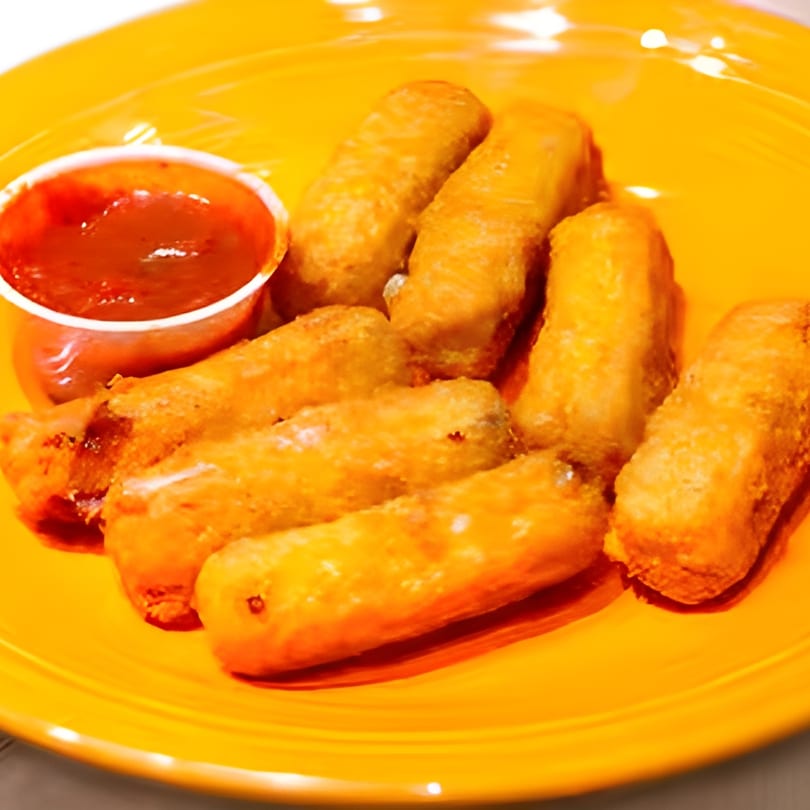 Golden-brown fried mozzarella sticks and a small cup of red dipping sauce on a bright orange plate.